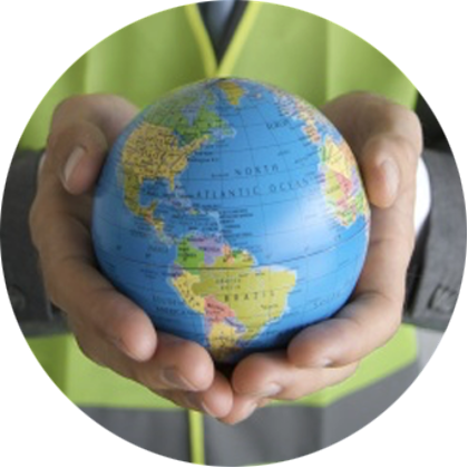 A close-up picture of a worker wearing a neon yellow vest holding a small globe with North and South America facing the camera in the palms of his hands.