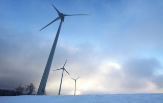An image of a wind turbine  jutting out of a snowy landscape.