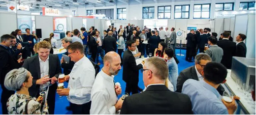 CWIEME attendees networking in a brightly lit convention space.