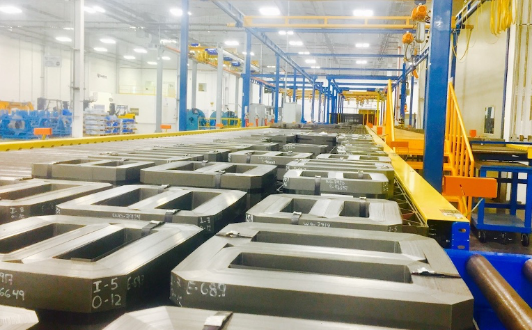 Corefficient’s electrical transformer core manufacturing line in Monterrey, Mexico. Close angle on multiple transformer cores in a brightly lit factory environment.