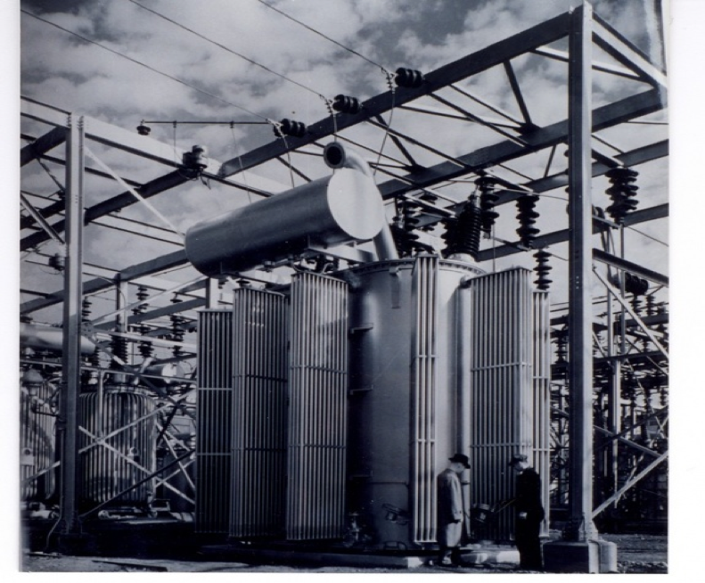 Two men standing in front of the transformer at Silver Lake Substation, the old General Electric Company, which Stanley began.