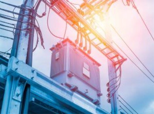 A silver electrical transformer core with the sun setting in the background.
